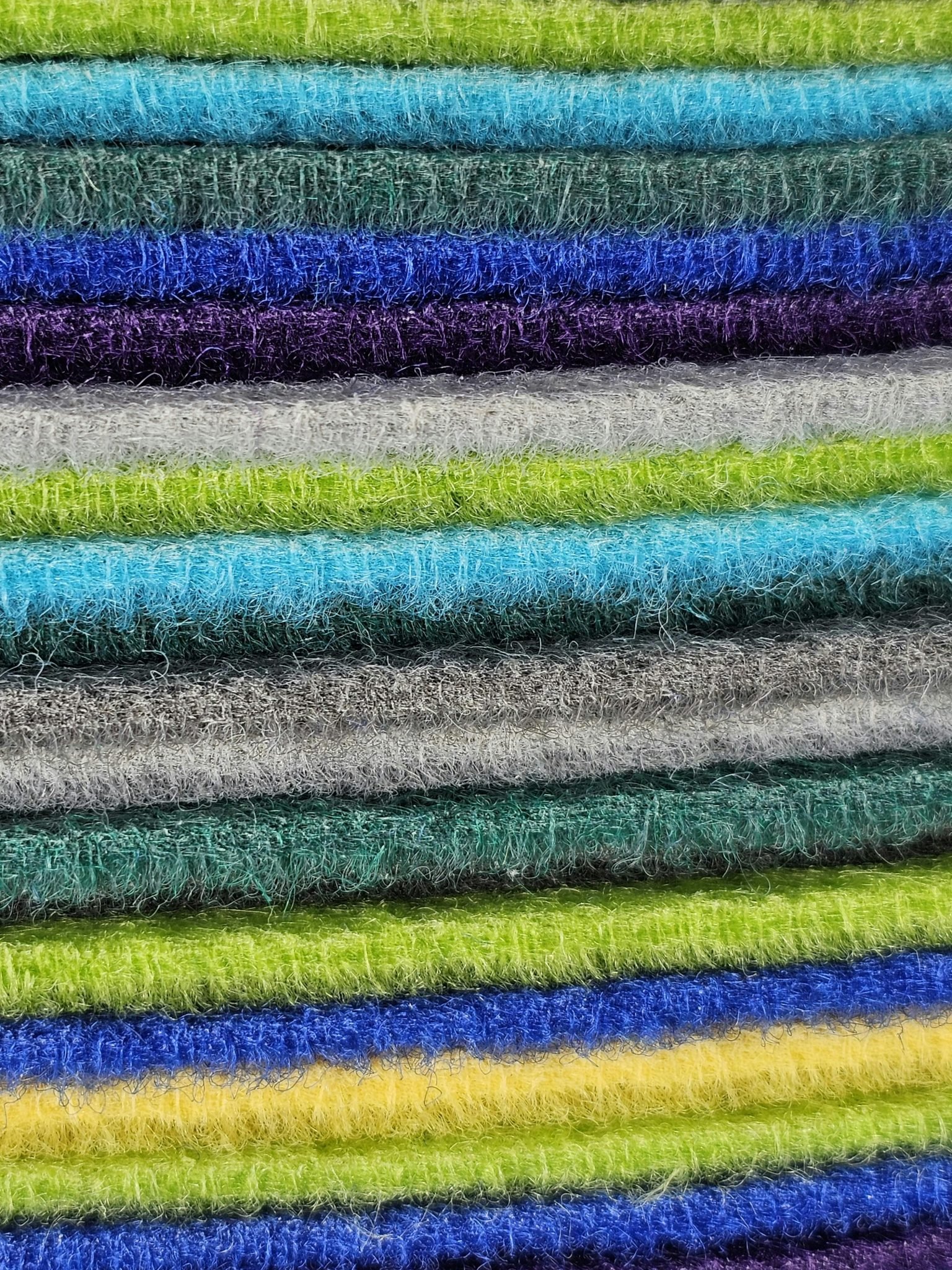Close-up view of vibrant and fluffy stacked fabric layers in various colors, showcasing texture and pattern.